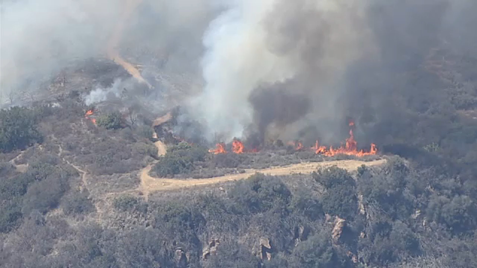 Crews battle brush fire threatening structures in Malibu
