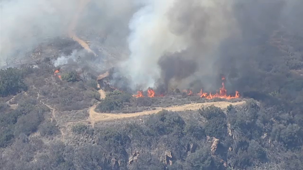 Crews battle brush fire threatening structures in Malibu