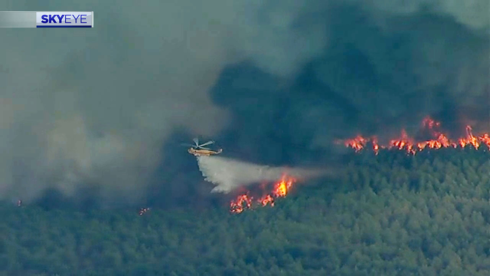 Firefighting aircraft flying over major fire in Walker County