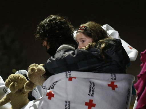 Eight-year old Shayne Frate, a third grade student at Sandy Hook Elementary School, hangs from her mother Valerie's back, wrapped in a Red Cross blanket to protect her from the cold, rainy weather, as she waits in line to attend an interfaith vigil with President Barack Obama, Sunday, Dec. 16, 2012, in Newtown, Conn. A gunman walked into Sandy Hook Elementary School in Newtown Friday and opened fire, killing 26 people, including 20 children. (AP Photo/Jason DeCrow)