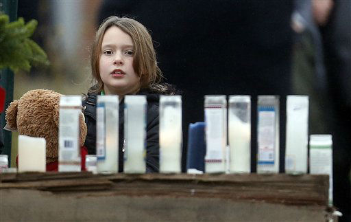 A young girl holding a teddy bear looks at a makeshift memorial outside of St. Rose of Lima Roman Catholic Church, Sunday, Dec. 16, 2012, in Newtown, Conn. On Friday, a gunman allegedly killed his mother at their home and then opened fire inside the Sandy Hook Elementary School in Newtown, killing 26 people, including 20 children.(AP Photo/Julio Cortez)