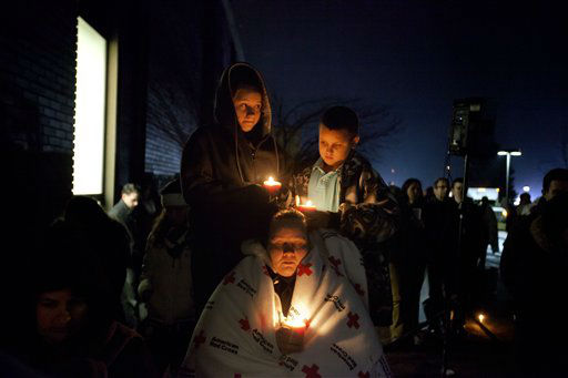 Sharon Bertrand, center, listens with her daughter Daysha, 13, left, and son Juan, all of Waterbury, Conn., to a memorial service over a loudspeaker outside Newtown High School for the victims of the Sandy Hook Elementary School shooting, Sunday, Dec. 16, 2012, in Newtown, Conn. (AP Photo/David Goldman)