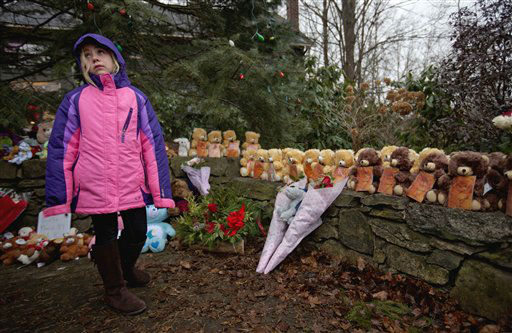 Ava Staiti, 7, of New Milford, Conn., looks up at her mother Emily Staiti, not pictured, while visiting a sidewalk memorial with 26 teddy bears, each representing a victim of the Sandy Hook Elementary School shooting, Sunday, Dec. 16, 2012, in Newtown, Conn. A gunman walked into Sandy Hook Elementary School in Newtown Friday and opened fire, killing 26 people, including 20 children. (AP Photo/David Goldman)