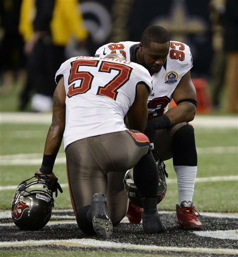 Tampa Bay Buccaneers outside linebacker Adam Hayward (57) and defensive tackle Gerald McCoy (93) pause for a moment of silence in memory of 20 children and six adults killed Friday in a shooting rampage at Sandy Hook Elementary School in Newtown, Conn., before an NFL football game against the New Orleans Saints at the Mercedes-Benz Superdome in New Orleans, Sunday, Dec. 16, 2012. (AP Photo/Bill Feig)