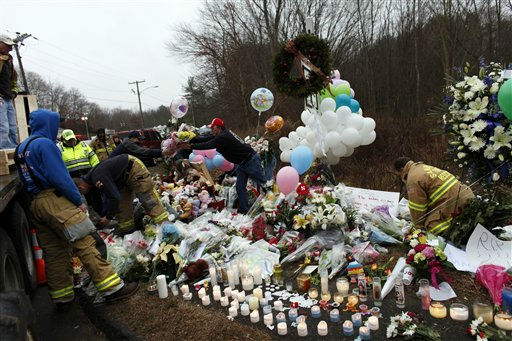 Firefighters and other volunteers reorganize a memorial for shooting victims near Sandy Hook Elementary School before erecting a shelter over it, Sunday, Dec. 16, 2012 in Newtown, Conn. A gunman walked into Sandy Hook Elementary School in Newtown Friday and opened fire, killing 26 people, including 20 children. (AP Photo/Jason DeCrow)