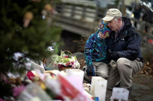 David Freedman, right, kneels with his son Zachary, 9, both of Newtown, Conn., as they visit a sidewalk memorial for the Sandy Hook Elementary School shooting victims, Sunday, Dec. 16, 2012, in Newtown, Conn. A gunman walked into Sandy Hook Elementary School in Newtown Friday and opened fire, killing 26 people, including 20 children. (AP Photo/David Goldman)