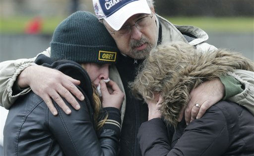 A man clutches two sobbing women at the site of a makeshift memorial for school shooting victims at the village of Sandy Hook in Newtown, Conn., Sunday, Dec. 16, 2012. A gunman opened fire at Sandy Hook Elementary School in the town, killing 26 people, including 20 children before killing himself on Friday. (AP Photo/Charles Krupa)