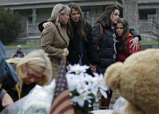 Women embrace at the site of a makeshift memorial for school shooting victims at the village of Sandy Hook in Newtown, Conn., Sunday, Dec. 16, 2012. A gunman opened fire at Sandy Hook Elementary School in the town, killing 26 people, including 20 children before killing himself on Friday. (AP Photo/Charles Krupa)