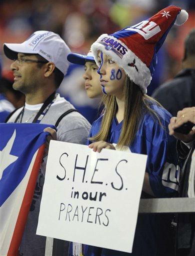 Makayla Ferfecki, of Kentucky, holds a sign honoring the victims of the shooting at Sandy Hook Elementary School in Newtown, Conn., before the first half of an NFL football game between the Atlanta Falcons and the New York Giants, Sunday, Dec. 16, 2012, in Atlanta. A gunman walked into the school Friday and opened fire, killing 26 people, including 20 children. (AP Photo/Mike Stewart)