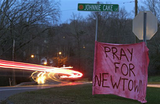 Tail lights streak past a sign asking for prayer on Main Street heading into the village of Newtown, Conn., at dusk Saturday, Dec. 15, 2012. A gunman opened fire at Sandy Hook Elementary School in the town, killing 26 people, including 20 children before killing himself on Friday. (AP Photo/Charles Krupa)