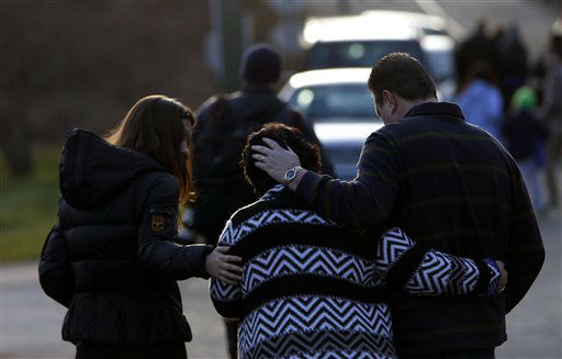 A woman is comforted after paying her respects at a memorial for shooting victims near Sandy Hook Elementary School, Saturday, Dec. 15, 2012 in Newtown, Conn. A gunman walked into Sandy Hook Elementary School in Newtown Friday and opened fire, killing 26 people, including 20 children. (AP Photo/Jason DeCrow)