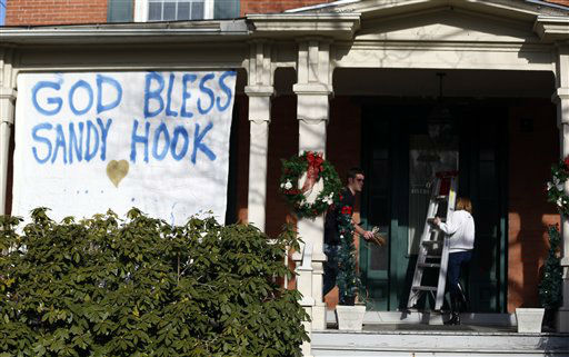 People collect items used to hang a message written on fabric at a home a day after a gunman opened fire at Sandy Hook Elementary School, Saturday, Dec. 15, 2012, in the Sandy Hook village of Newtown, Conn. The massacre of 26 children and adults at Sandy Hook Elementary school elicited horror and soul-searching around the world even as it raised more basic questions about why the gunman, 20-year-old Adam Lanza, would have been driven to such a crime and how he chose his victims. (AP Photo/Julio Cortez)