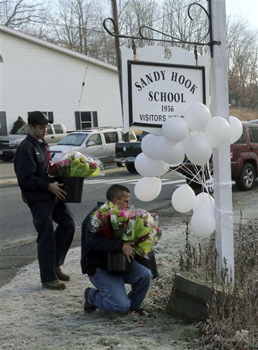 Volunteer firefighters place flowers at a makeshift memorial at a sign for the Sandy Hook Elementary school Saturday, Dec. 15, 2012 in the Sandy Hook village of Newtown, Conn. The massacre of 26 children and adults at Sandy Hook Elementary school elicited horror and soul-searching around the world even as it raised more basic questions about why the gunman, 20-year-old Adam Lanza, would have been driven to such a crime and how he chose his victims. (AP Photo/Mary Altaffer)