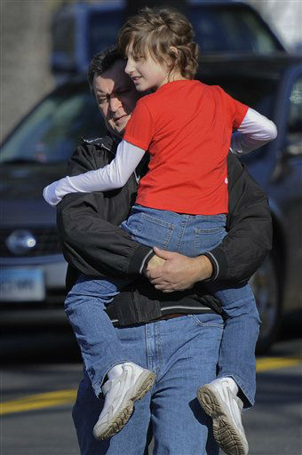 A man carries a child away from the area of a shooting at the Sandy Hook Elementary School in Newtown, Conn., about 60 miles (96 kilometers) northeast of New York City, Friday, Dec. 14, 2012. A man opened fire Friday inside two classrooms at the school where his mother worked as a teacher, killing 26 people, including 20 children. The killer, armed with two handguns, committed suicide at the school and another person was found dead at a second scene, bringing the toll to 28, authorities said. A law enforcement official identified the gunman as 20-year-old Adam Lanza. (AP Photo/Jessica Hill)
