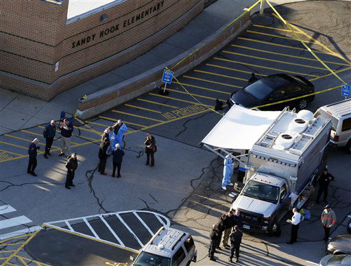 Officials are on the scene outside of Sandy Hook Elementary School in Newtown, Conn., where authorities say a gunman opened fire inside an elementary school in a shooting that left 27 people dead, including 18 children, Friday, Dec. 14, 2012. (AP Photo/Julio Cortez)