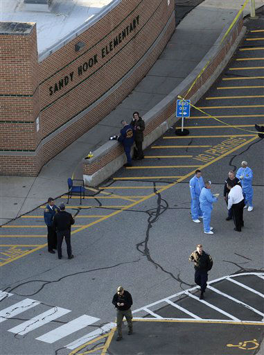 Officials are on the scene outside of Sandy Hook Elementary School in Newtown, Conn., where authorities say a gunman opened fire inside an elementary school in a shooting that left 27 people dead, including 18 children, Friday, Dec. 14, 2012. (AP Photo/Julio Cortez)