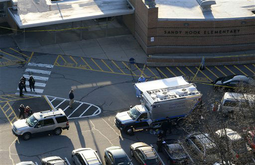 Officials are on the scene outside of Sandy Hook Elementary School in Newtown, Conn., where authorities say a gunman opened fire inside an elementary school in a shooting that left 27 people dead, including 18 children, Friday, Dec. 14, 2012. (AP Photo/Julio Cortez)