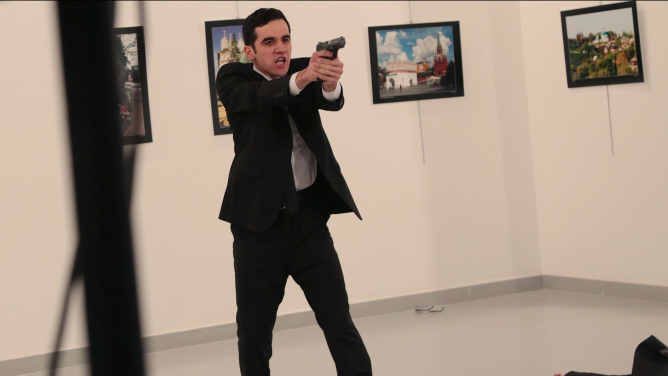 An unnamed gunman gestures after shooting the Russian Ambassador to Turkey, Andrei Karlov, at a photo gallery in Ankara, Turkey, Monday, Dec. 19, 2016.