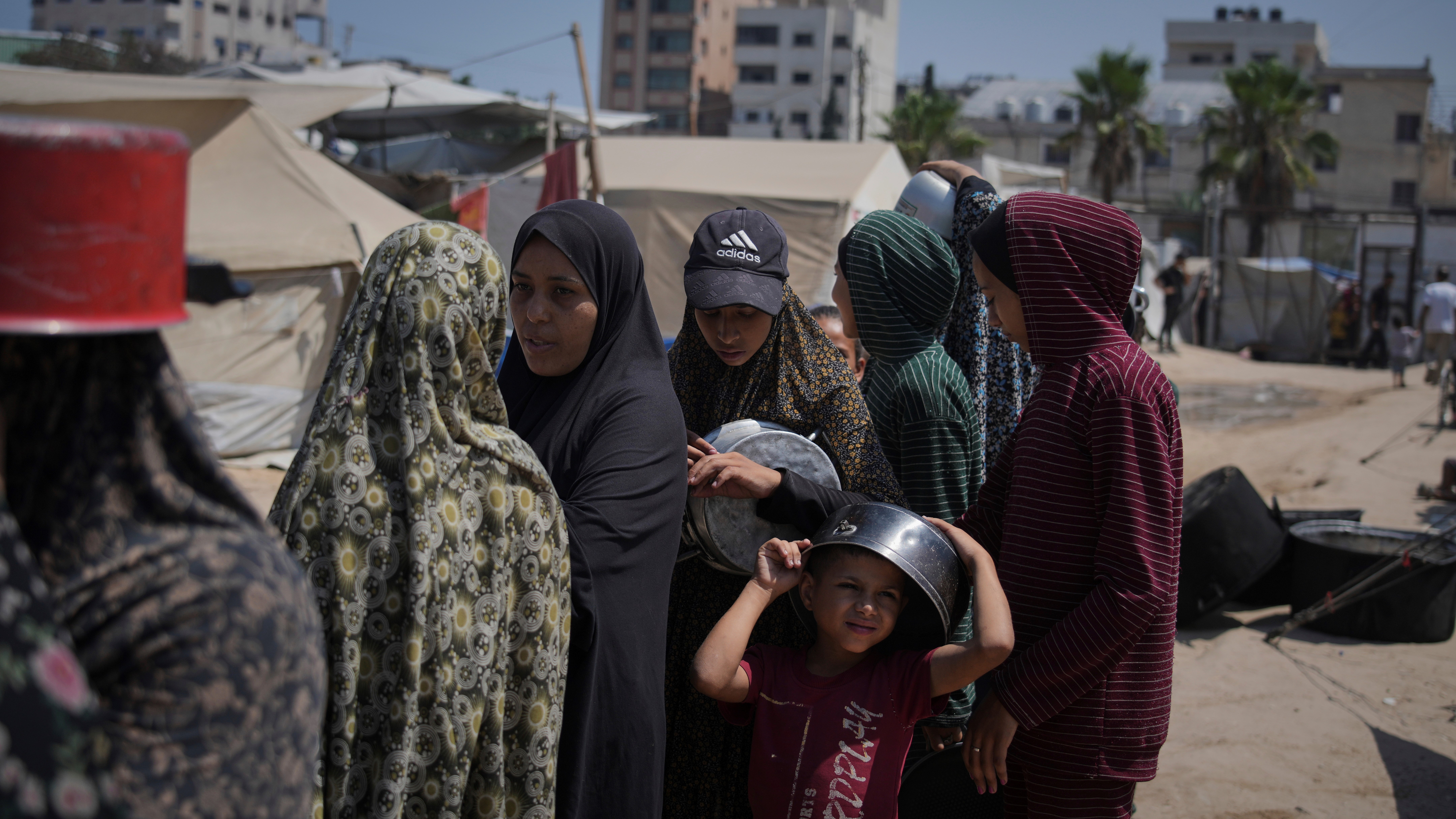 Displaced Palestinians wait for donated food at a community kitchen in Gaza City, northern Gaza Strip, Tuesday, July 22, 2025.