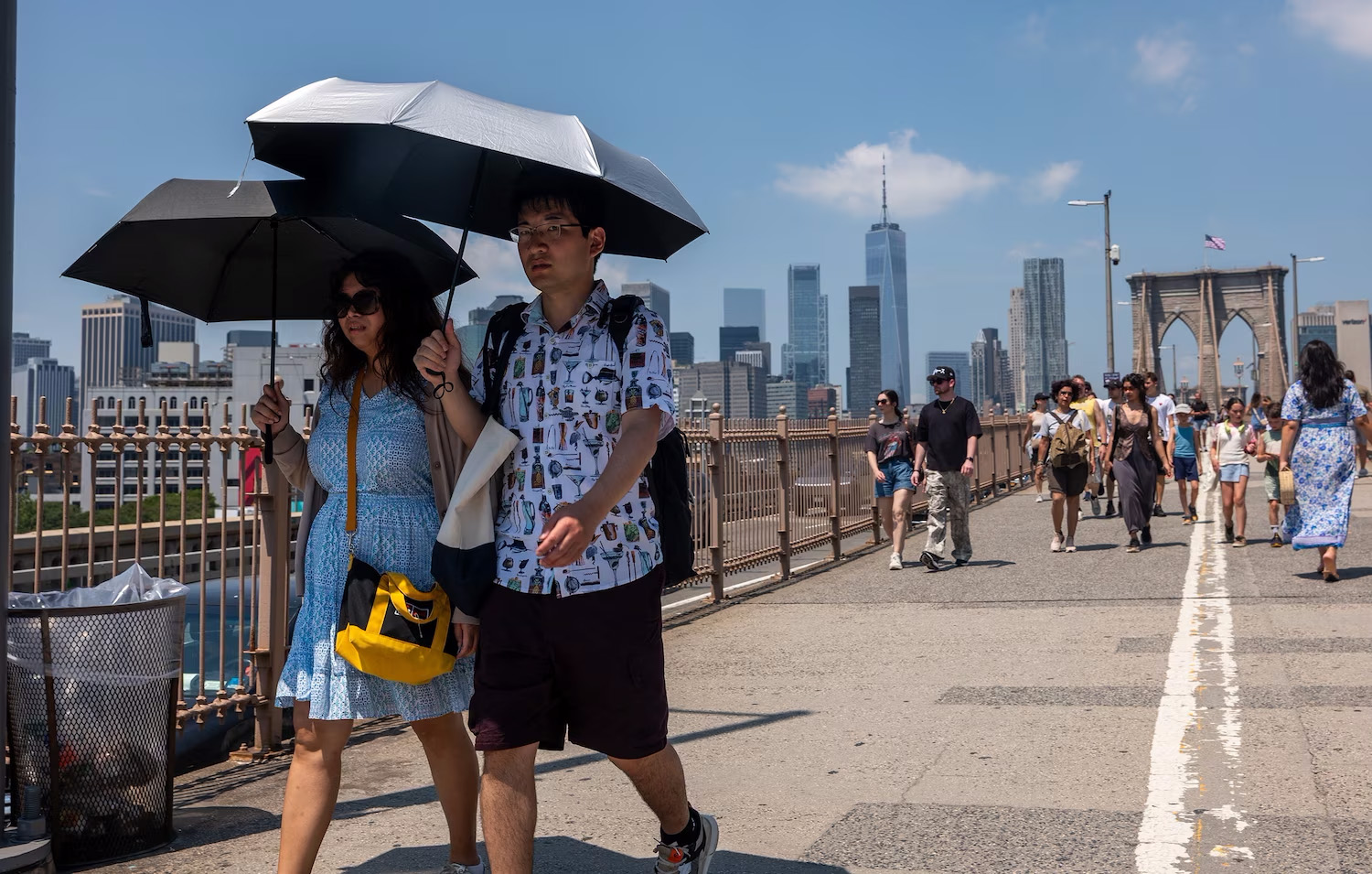 People walk across the Brooklyn Bridge in New York on a day where the heat index topped 100 degrees, July 25, 2025. 