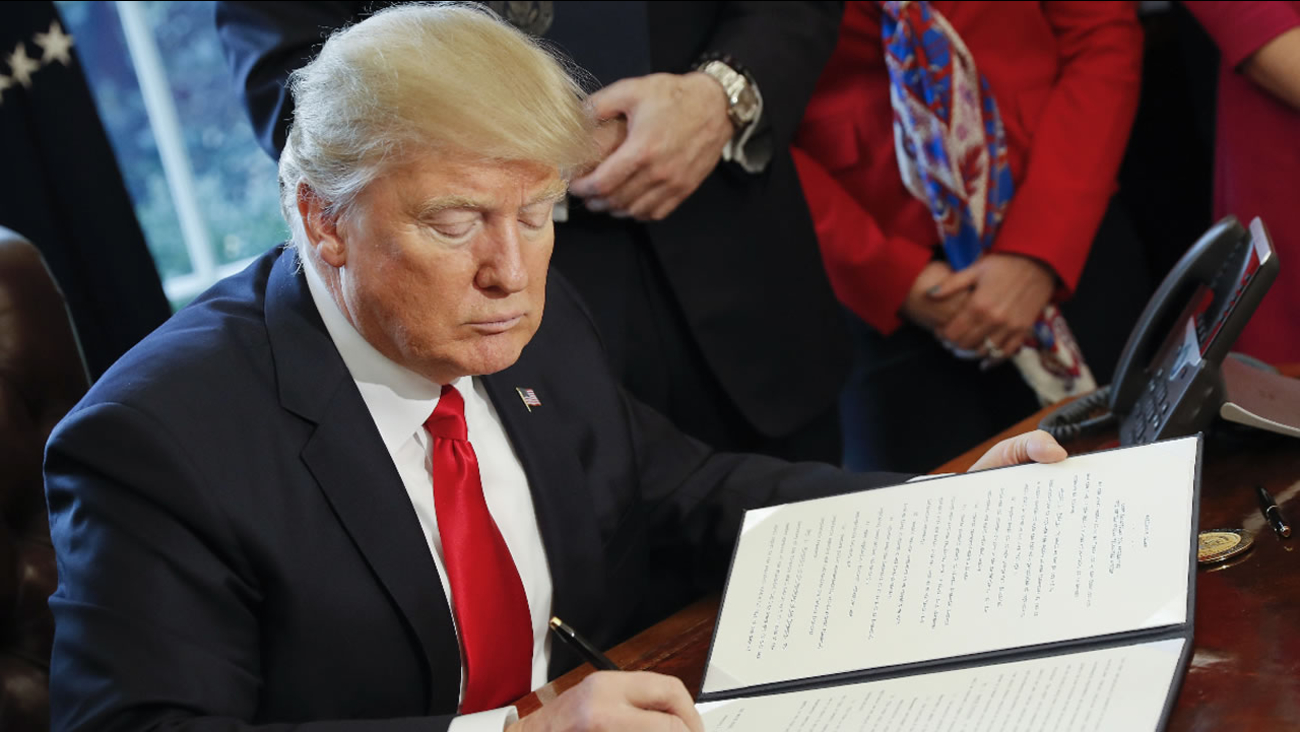 President Donald Trump signs an executive order in the Oval Office of the White House in Washington, Friday, Feb. 3, 2017.