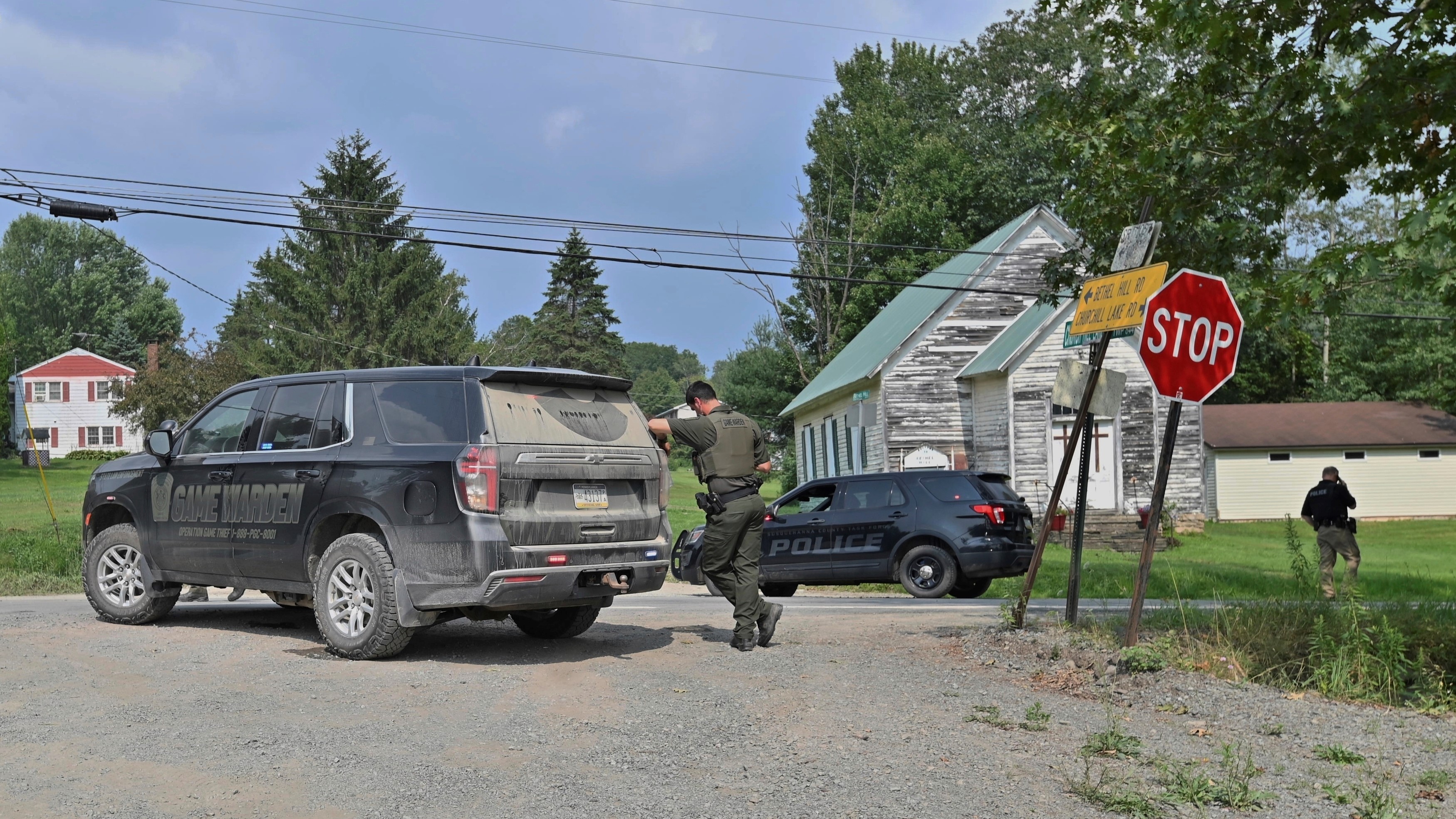 Police officers block a street leading to where two Pennsylvania state troopers were shot Thursday, Aug. 7, 2025, near the village of Thompson in Susquehanna County, Pa.