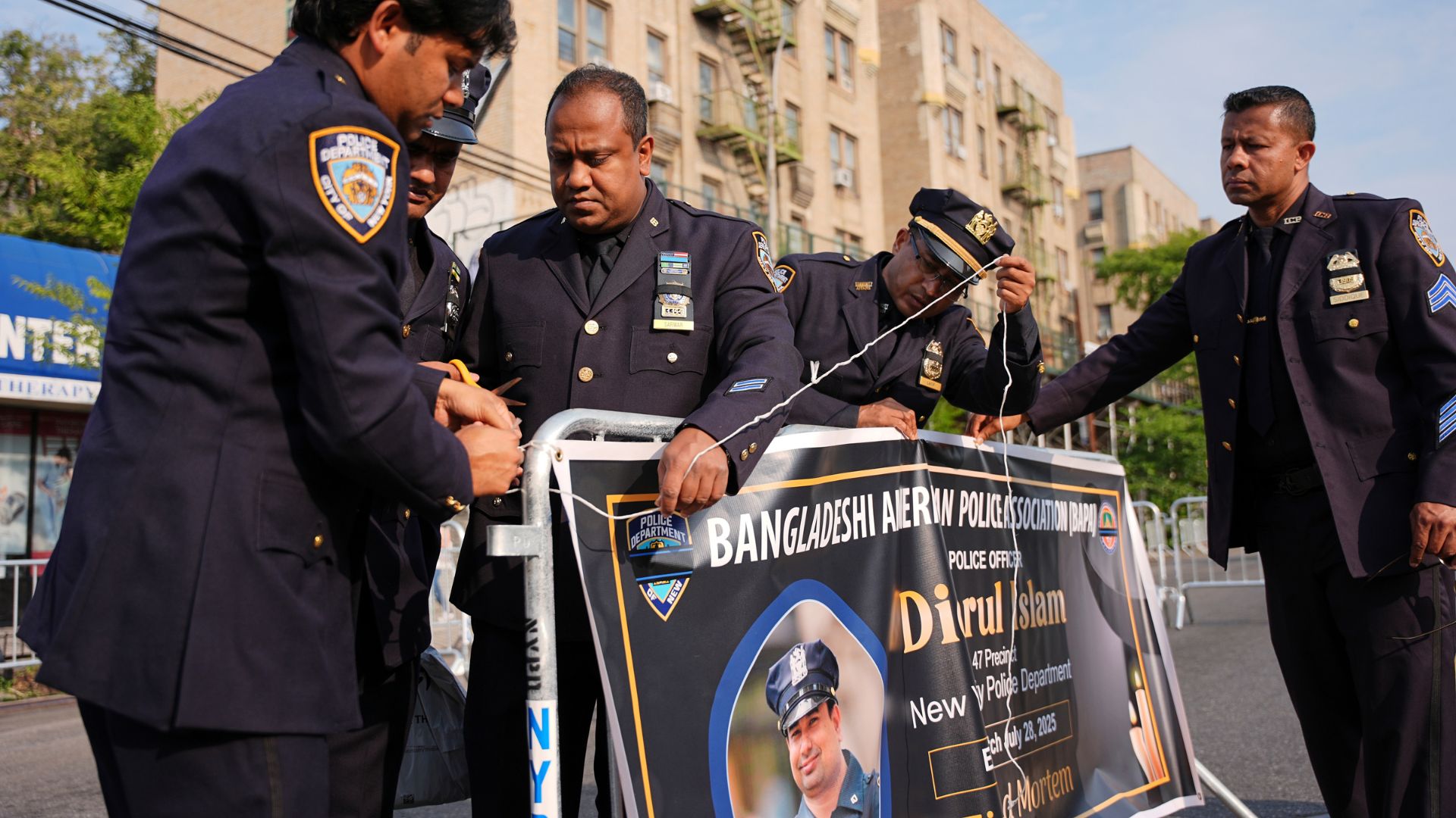 New York Police officers hang a banner for the funeral of officer Didarul Islam, Thursday, July 31, 2025, in New York.