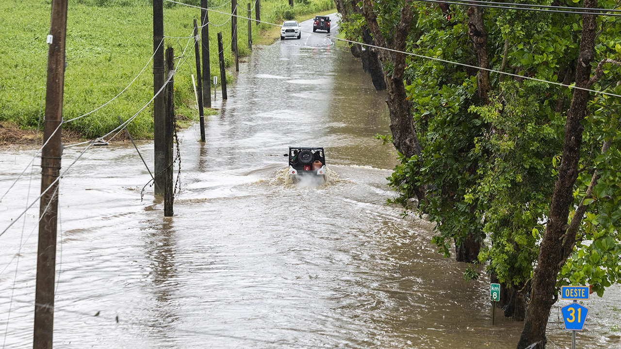 Vehicles traverse a flooded road in Naguabo, Puerto Rico, as Hurricane Erin brings heavy rain to the island on Sunday.