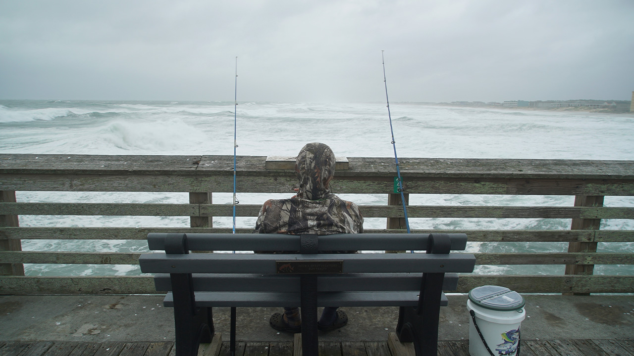 Sebastian Kettner fishes on Jennette's Pier as waves from Hurricane Erin crash ashore in Nags Head, N.C., Thursday, Aug. 21, 2025.