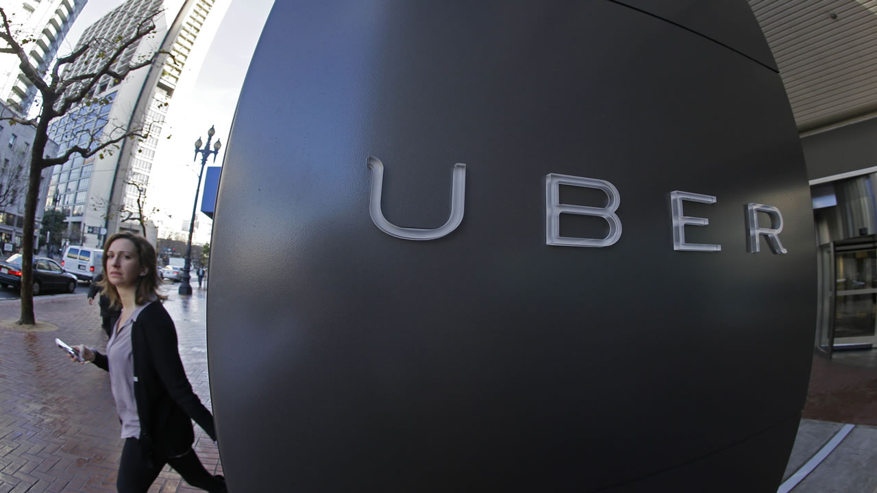 A woman walks past the company logo of the internet car service, Uber, in San Francisco on Dec. 16, 2014.