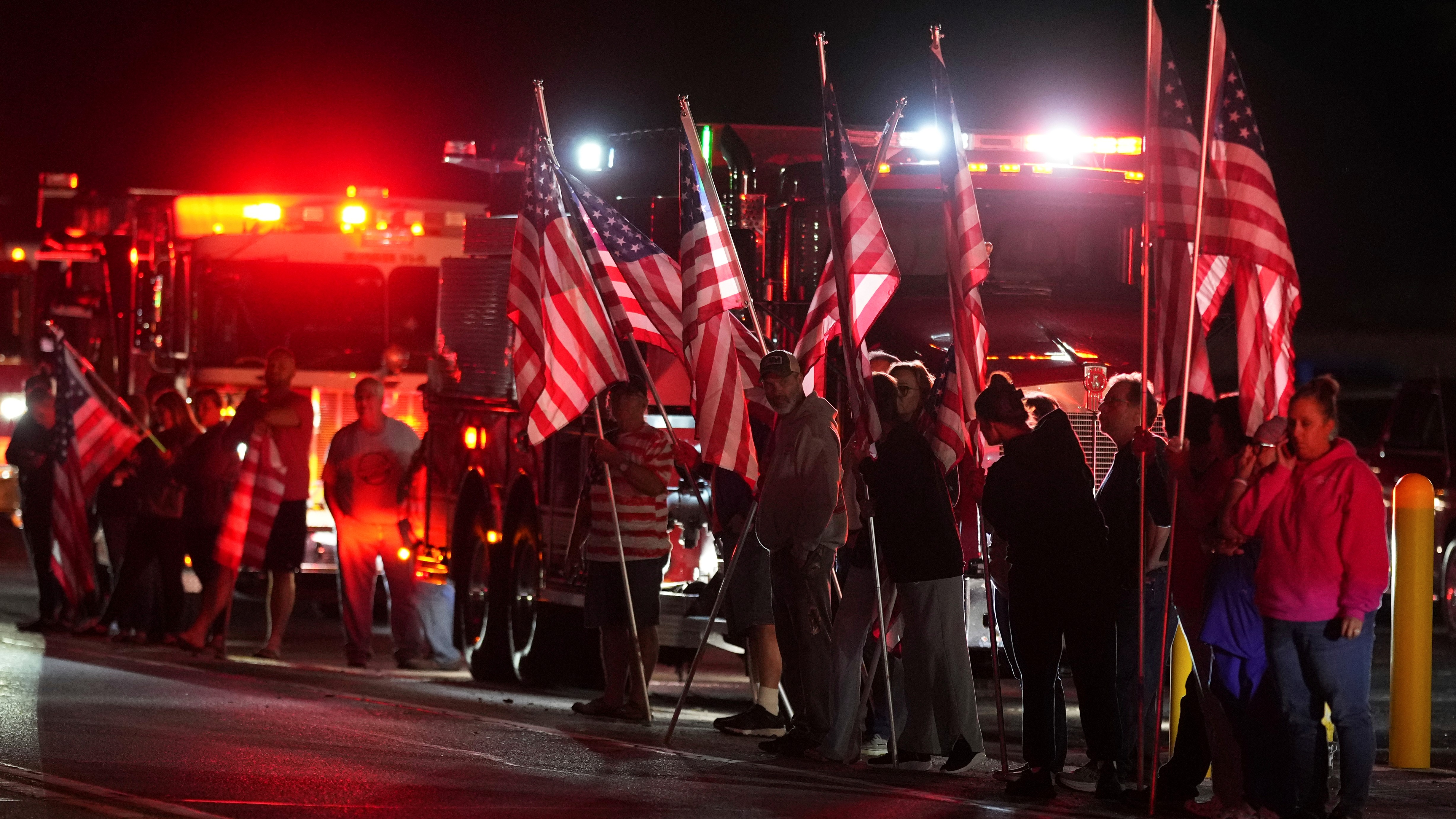 People hold American flags before a procession Wednesday, Sept. 17, 2025, in Spring Grove, Pa., after multiple police officers were shot and killed.