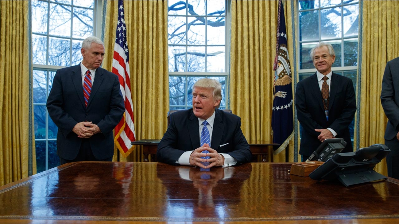 Vice President Mike Pence, left, and National Trade Council adviser Peter Navarro, right, wait for President Donald Trump to sign three executive orders, Monday, Jan. 23, 2017