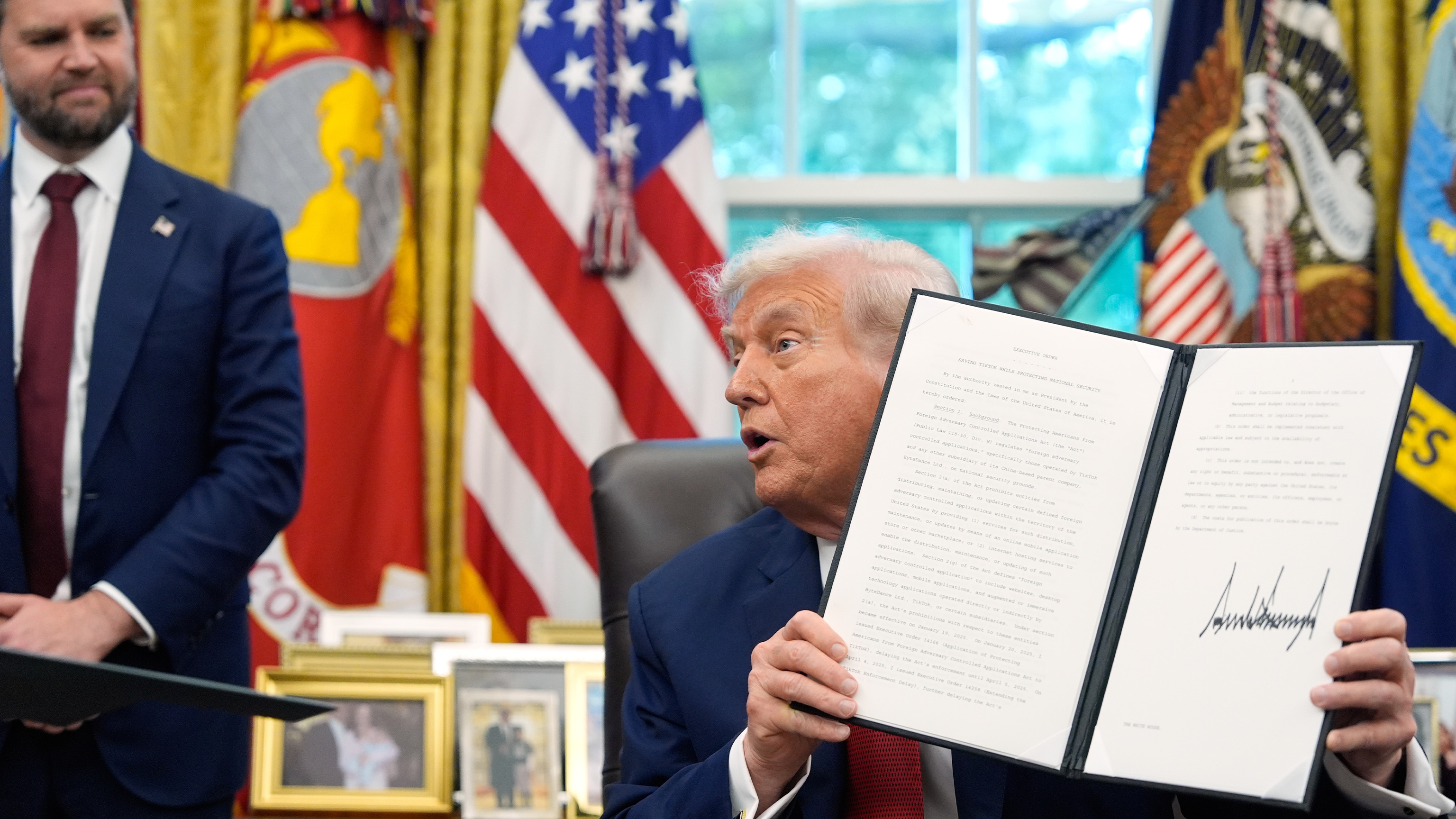 President Donald Trump holds a signed executive order regarding TikTok in the Oval Office at the White House, Thursday, Sept. 25, 2025, in Washington, as Vice President JD Vance watches.