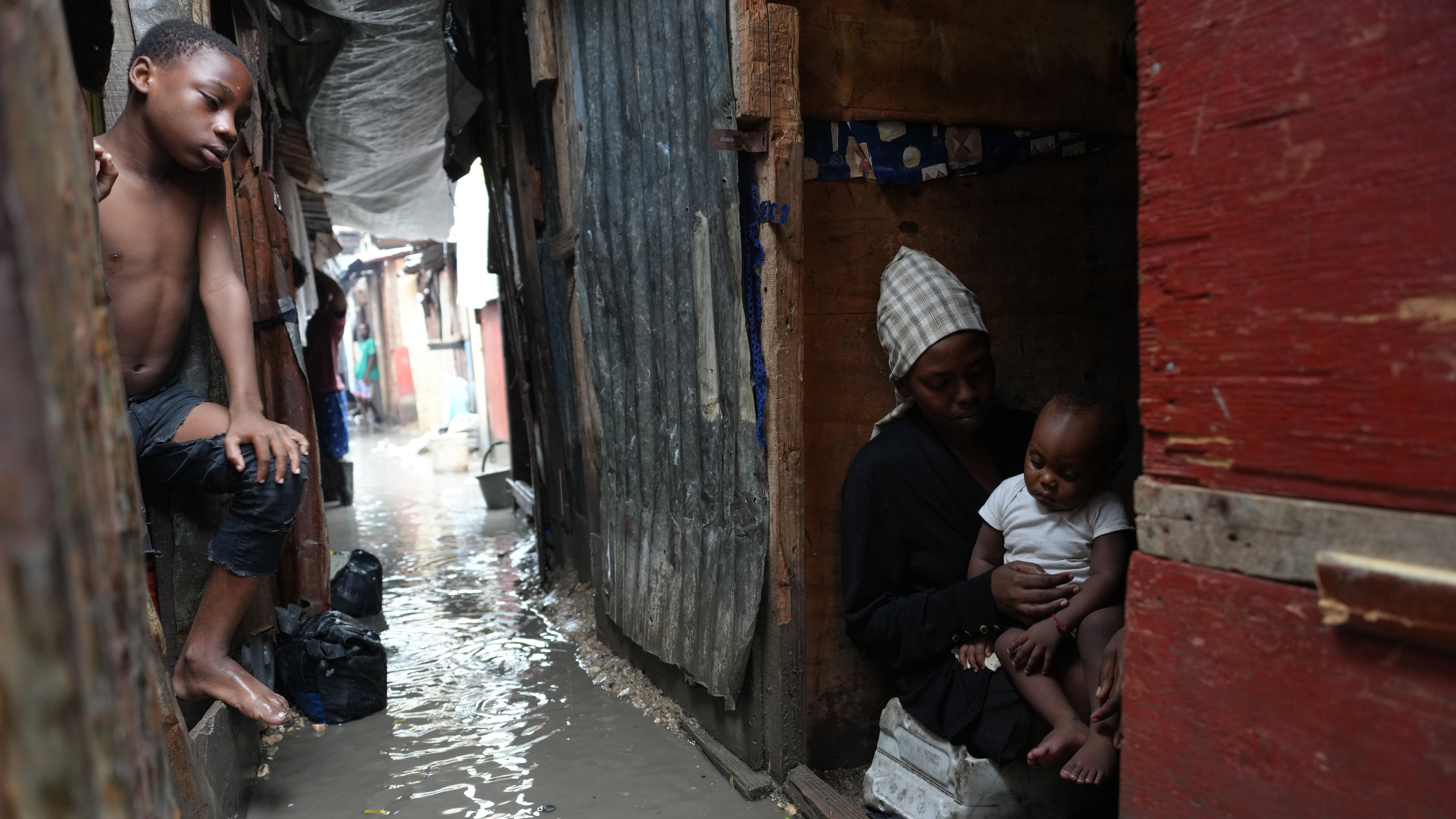 People stay inside a shelter for families displaced by gang violence, flooded by rain brought by Hurricane Melissa, in Port-au-Prince, Haiti, Wednesday, Oct. 29, 2025.