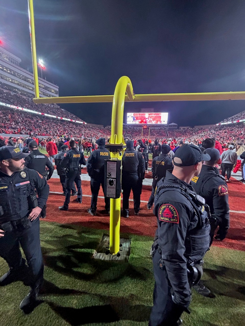 NC State goal post surrounded by Raleigh officers after fans storm the field in upset win over Georgia Tech.