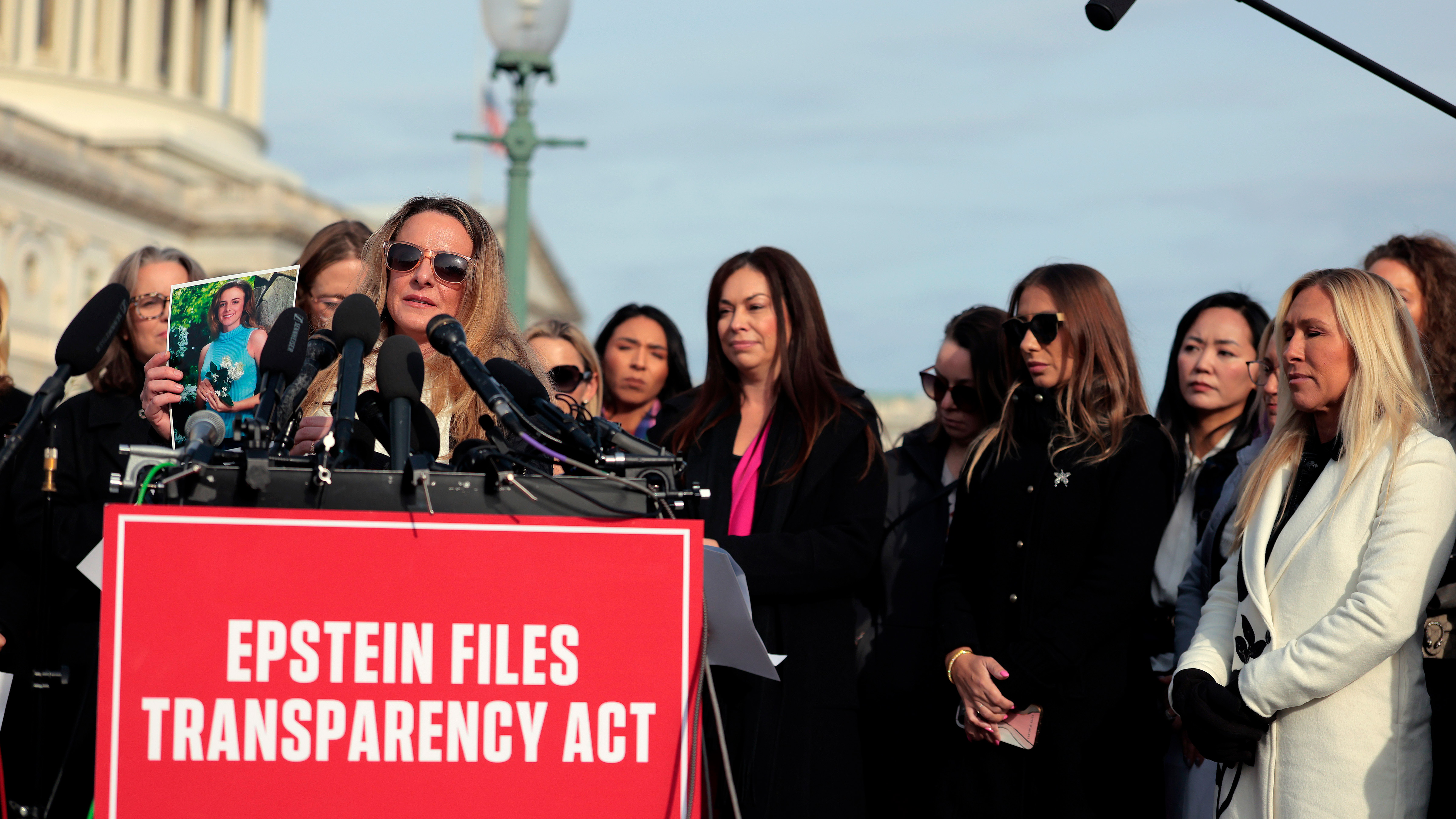 Epstein abuse survivor Ashley Rubright holds up a photo of her younger self during a news conference with lawmakers on the Epstein Files Transparency Act outside the U.S. Capitol on November 18, 2025 in Washington, DC.