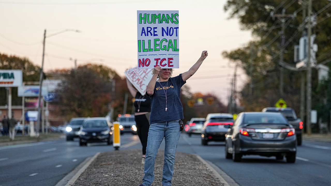 Protesters holds signs amidst the arrival of federal law enforcement, Monday, Nov. 17, 2025, in Charlotte, N.C.
