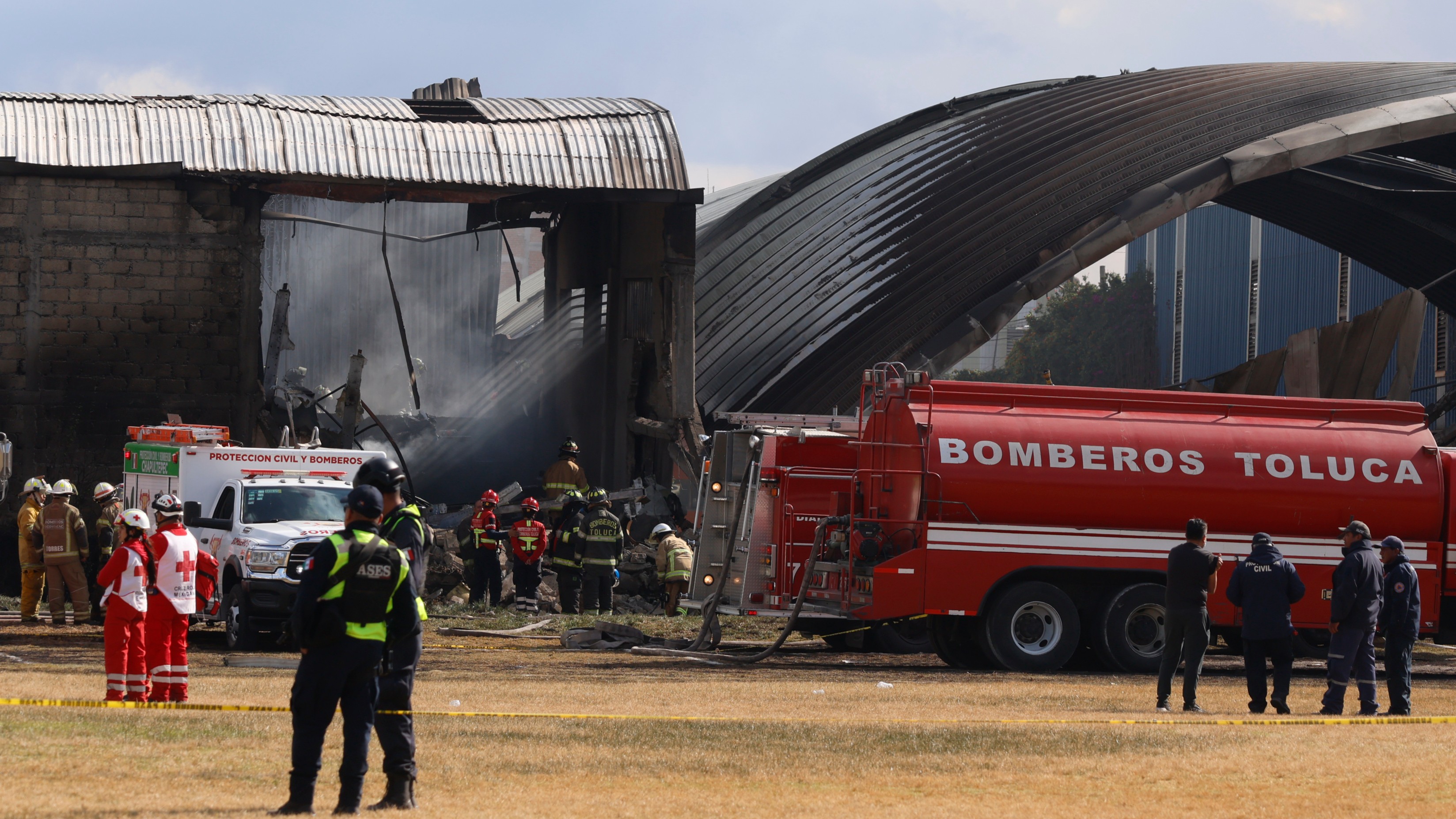 Firefighters and Red Cross workers arrive at the scene of a plane crash near Toluca Airport in San Mateo Atenco, Mexico, on Monday, December 15, 2025. (AP Photo/Ramsés Mercado)
