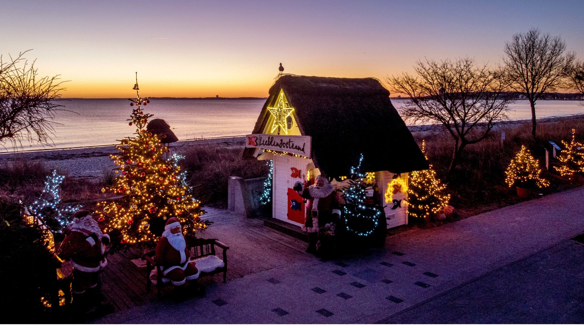 Christmas trees and Santa Clauses decorate the entrance to the beach in Haffkrug, northern Germany, Monday, Dec. 20, 2021.