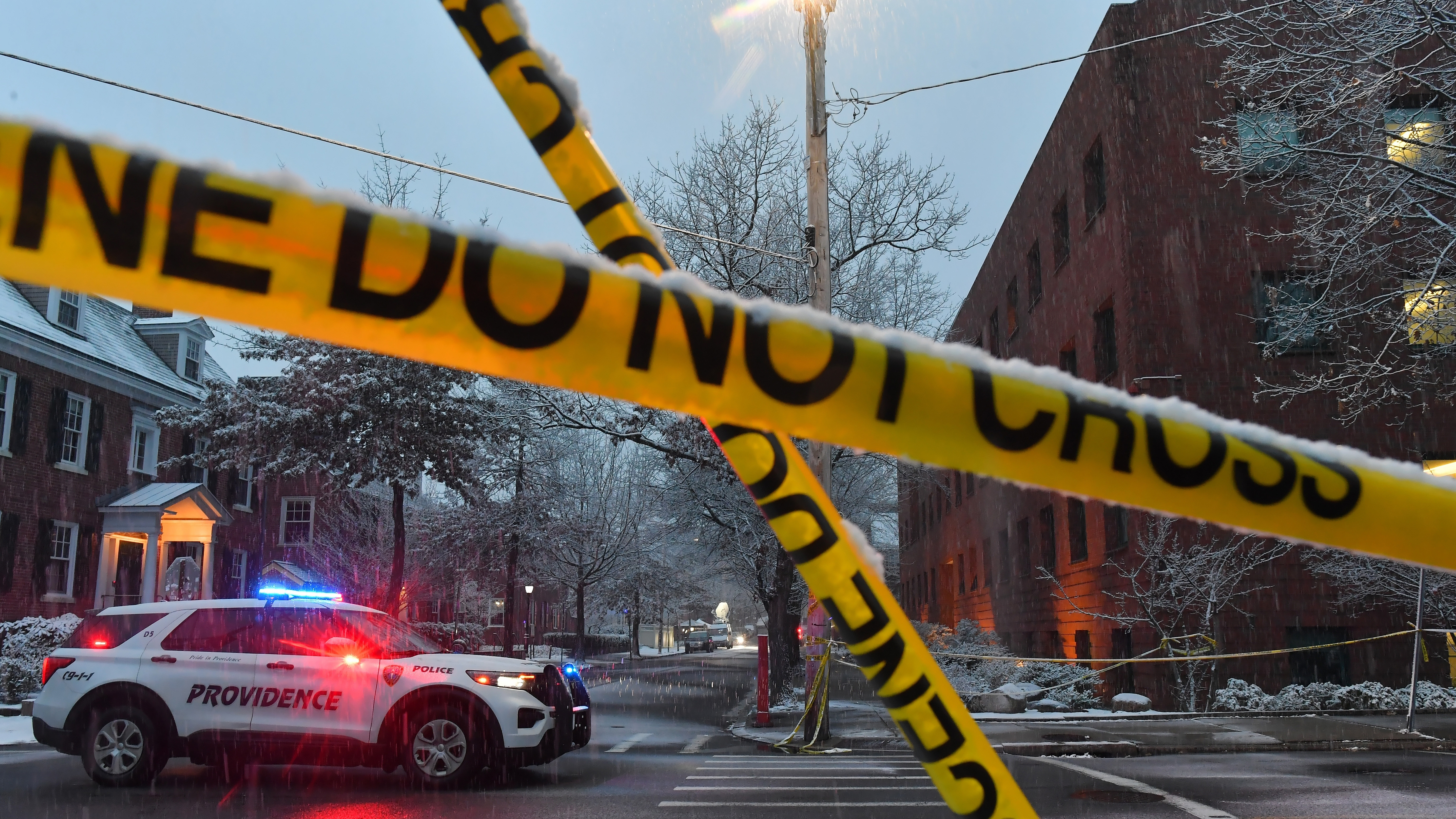 A police vehicle is parked at an intersection near crime scene tape at Brown University, Sunday, Dec. 14, 2025, in Providence, R.I., following a Saturday shooting at the university.