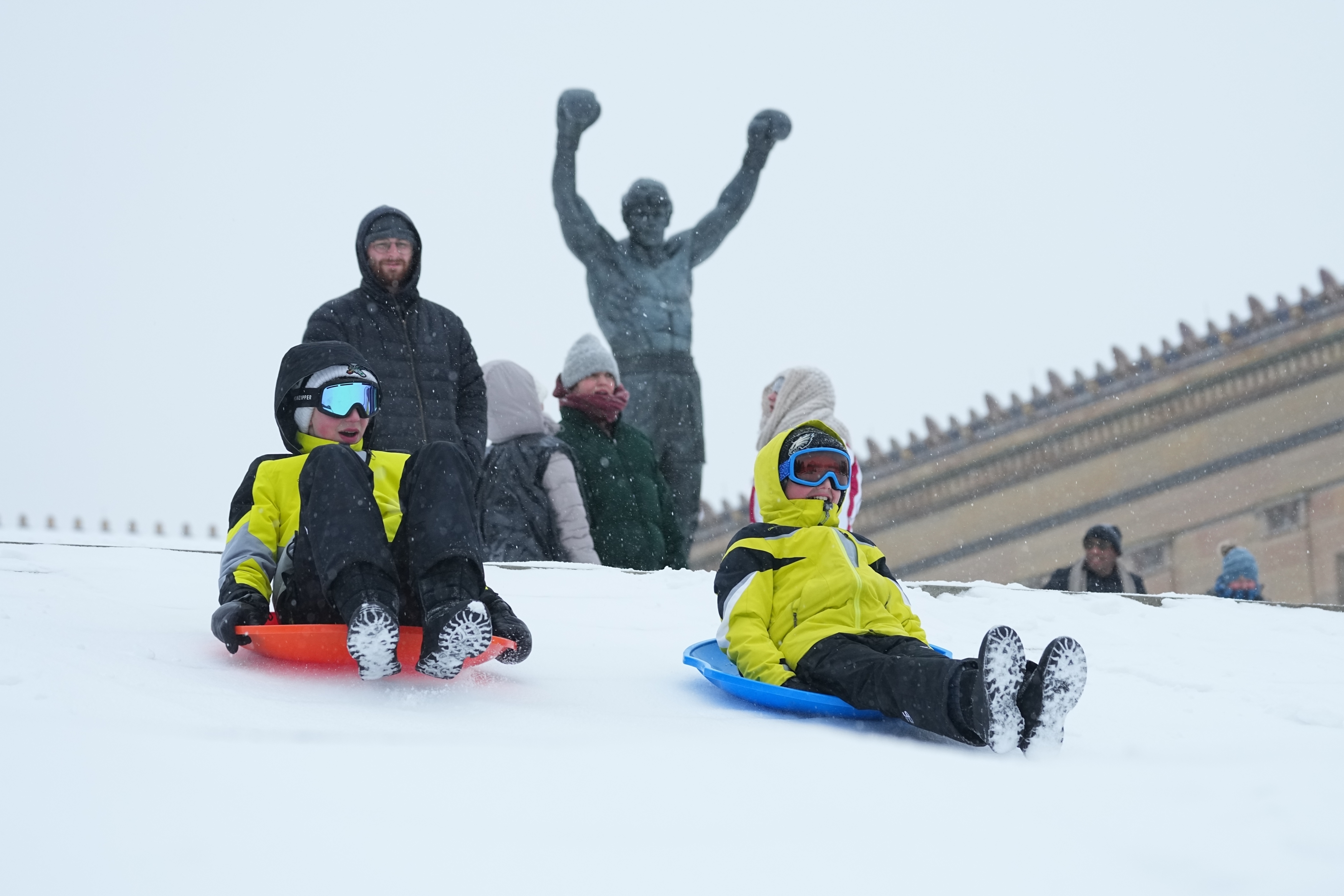 People sled at Philadelphia Art Museum steps by the Rocky statue during a winter storm on Sunday, Jan. 25, 2026.