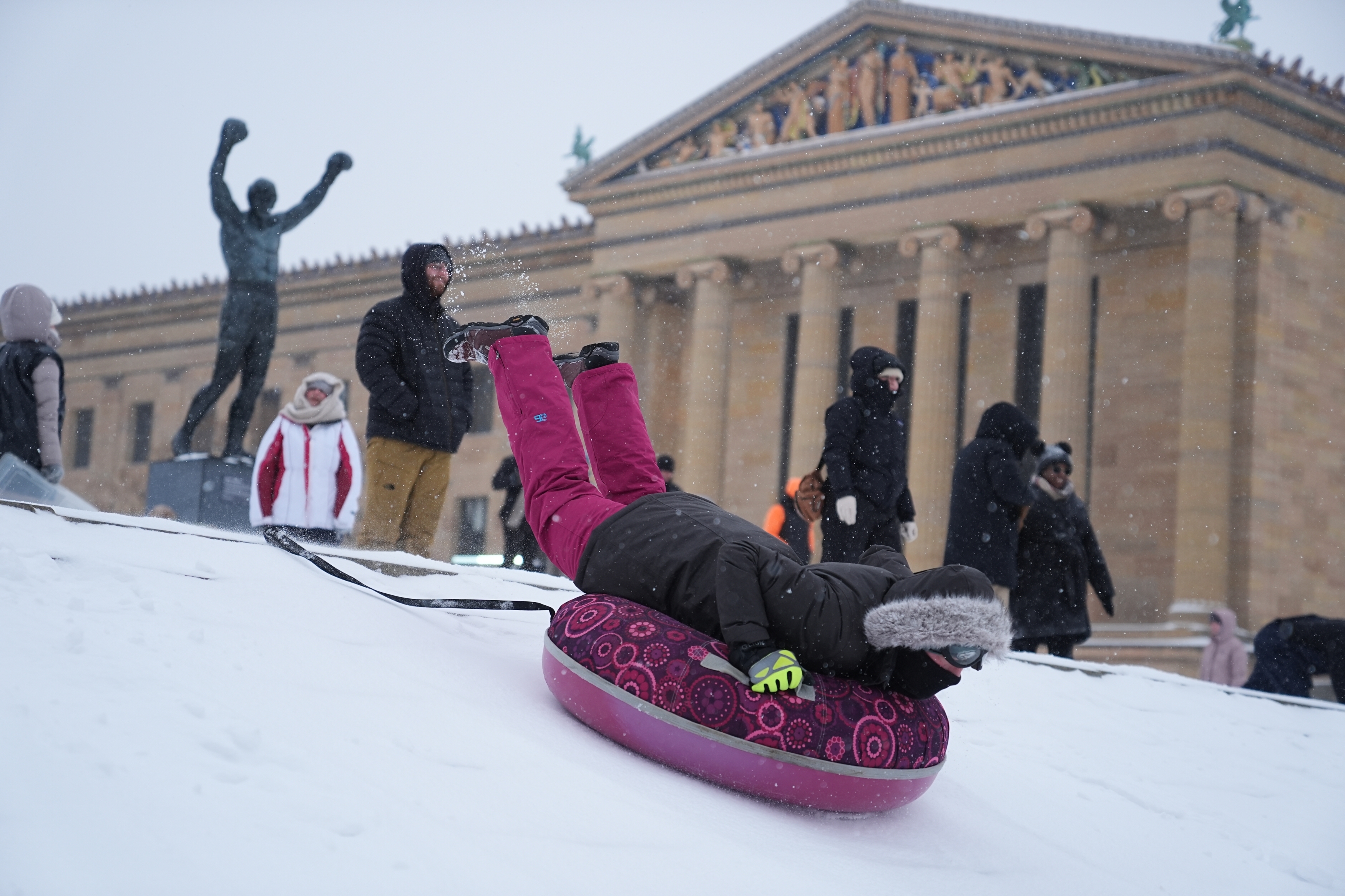 People sled at Philadelphia Art Museum steps by the Rocky statue during a winter storm on Sunday, Jan. 25, 2026.