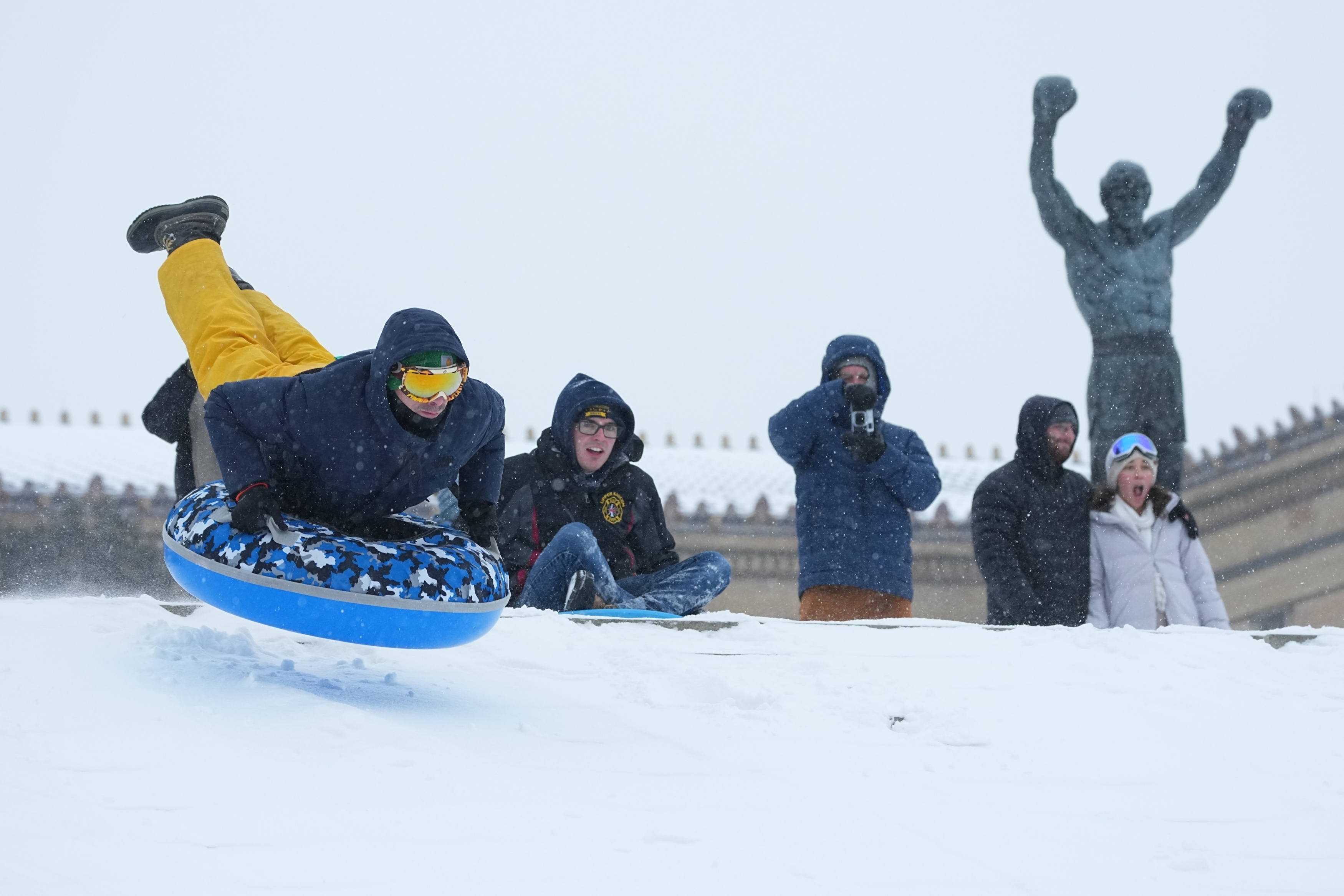 People sled at Philadelphia Art Museum steps by the Rocky statue during a winter storm on Sunday, Jan. 25, 2026.