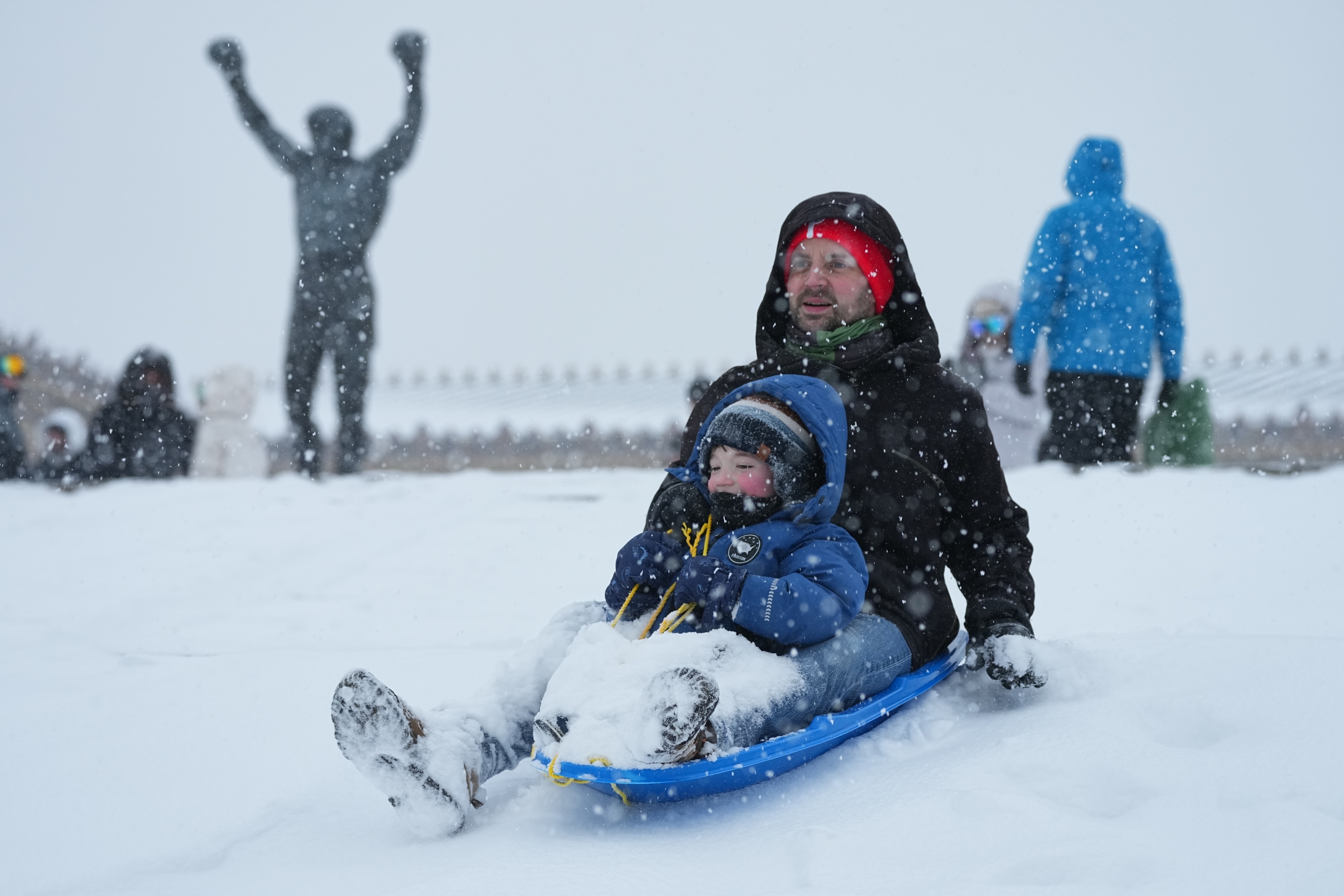 People sled at Philadelphia Art Museum steps by the Rocky statue during a winter storm on Sunday, Jan. 25, 2026.
