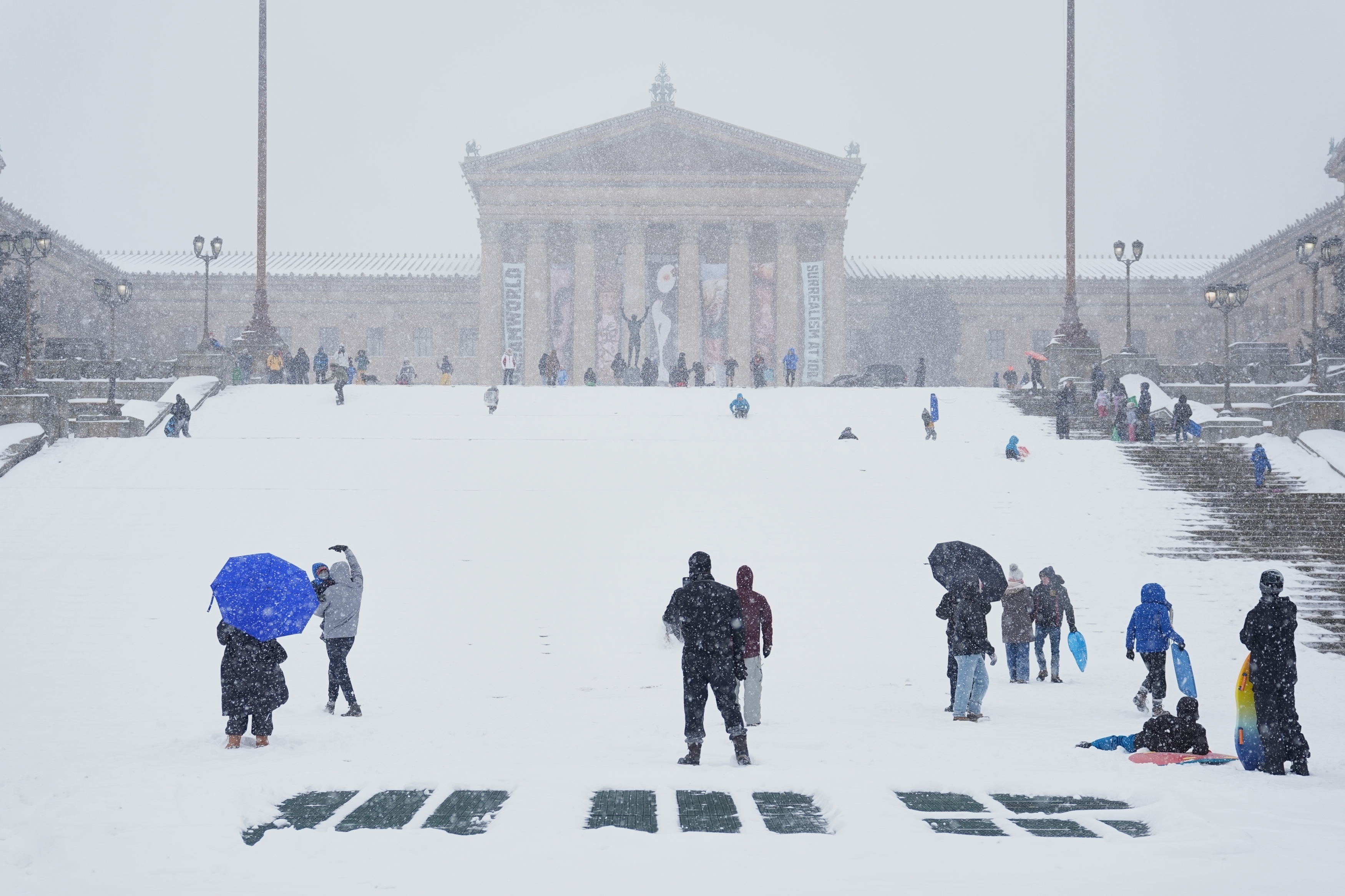 People sled at Philadelphia Art Museum steps by the Rocky statue during a winter storm on Sunday, Jan. 25, 2026.