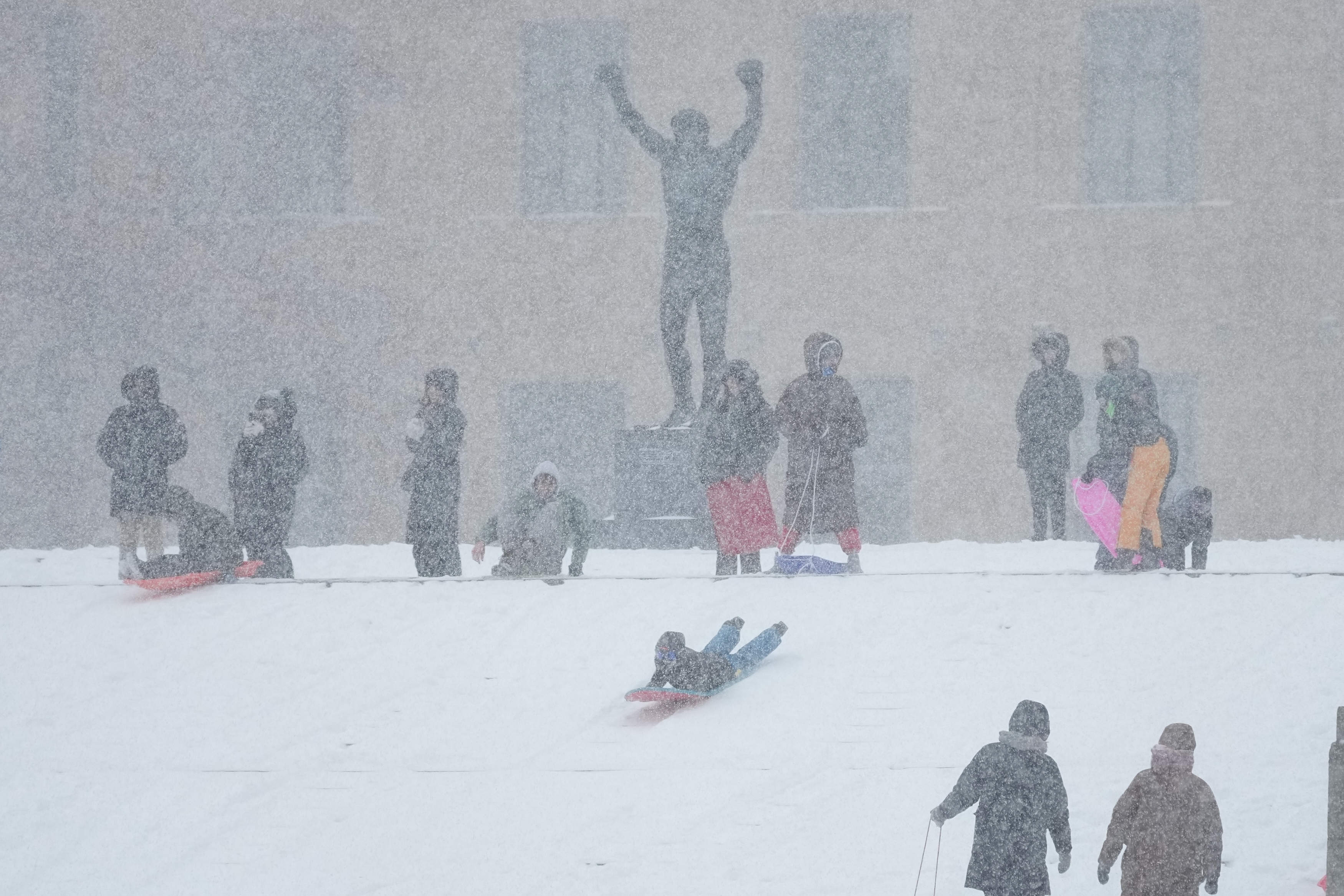People sled at Philadelphia Art Museum steps by the Rocky statue during a winter storm on Sunday, Jan. 25, 2026.