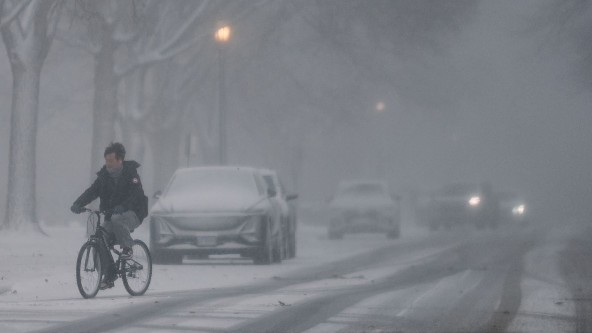 A person rides a bicycle through blowing snow, Wednesday, Jan. 14, 2026, in Evanston, Ill., a suburb of Chicago.