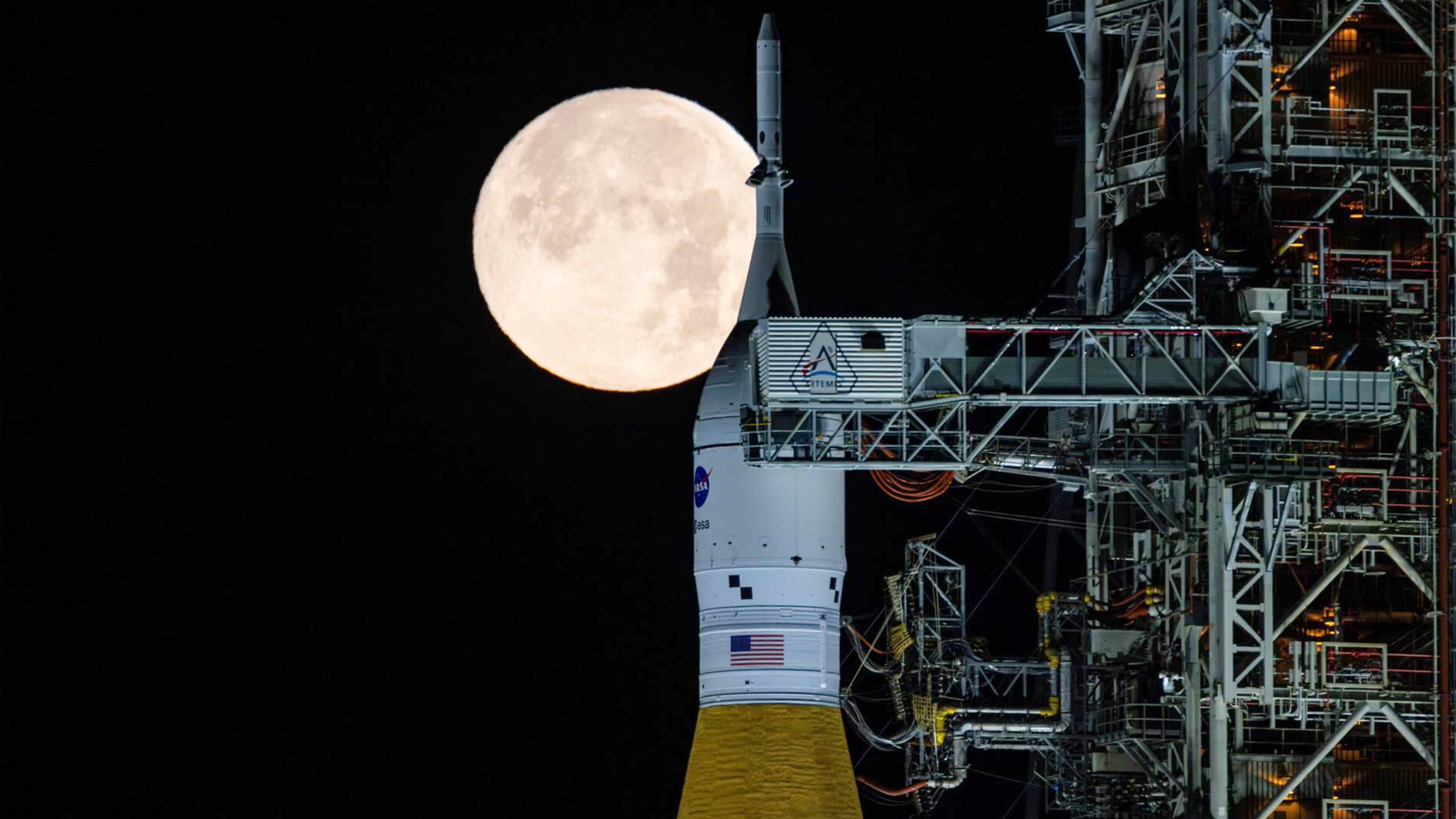 A full moon is seen shining over NASA's SLS (Space Launch System) and Orion spacecraft, atop the mobile launcher in the early hours of Sunday, Feb. 1, 2026, at NASA's Kennedy Space Center in Florida.