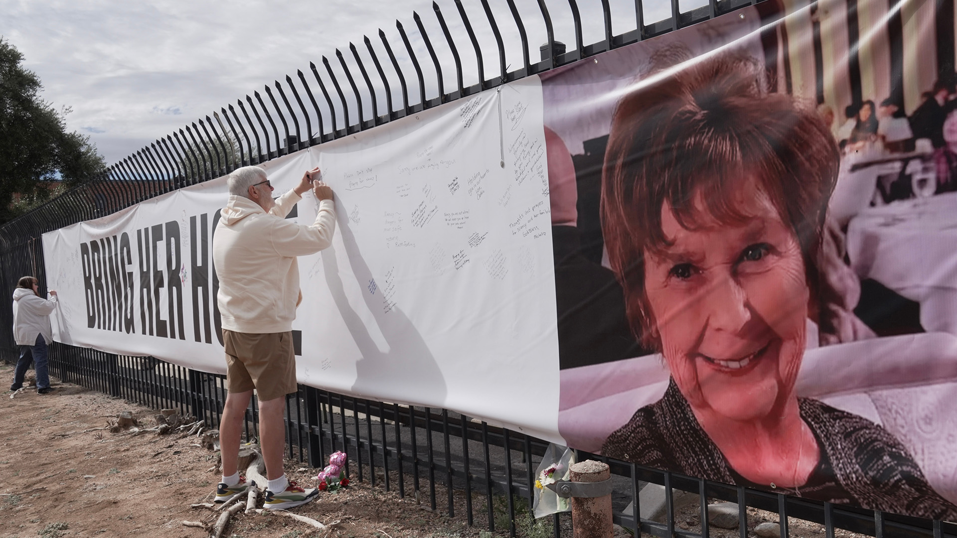 Jeff Robb, a Seattle resident wintering in Tucson, signs a banner supporting Nancy Guthrie in Tucson Ariz., on Friday, Feb. 13, 2026.