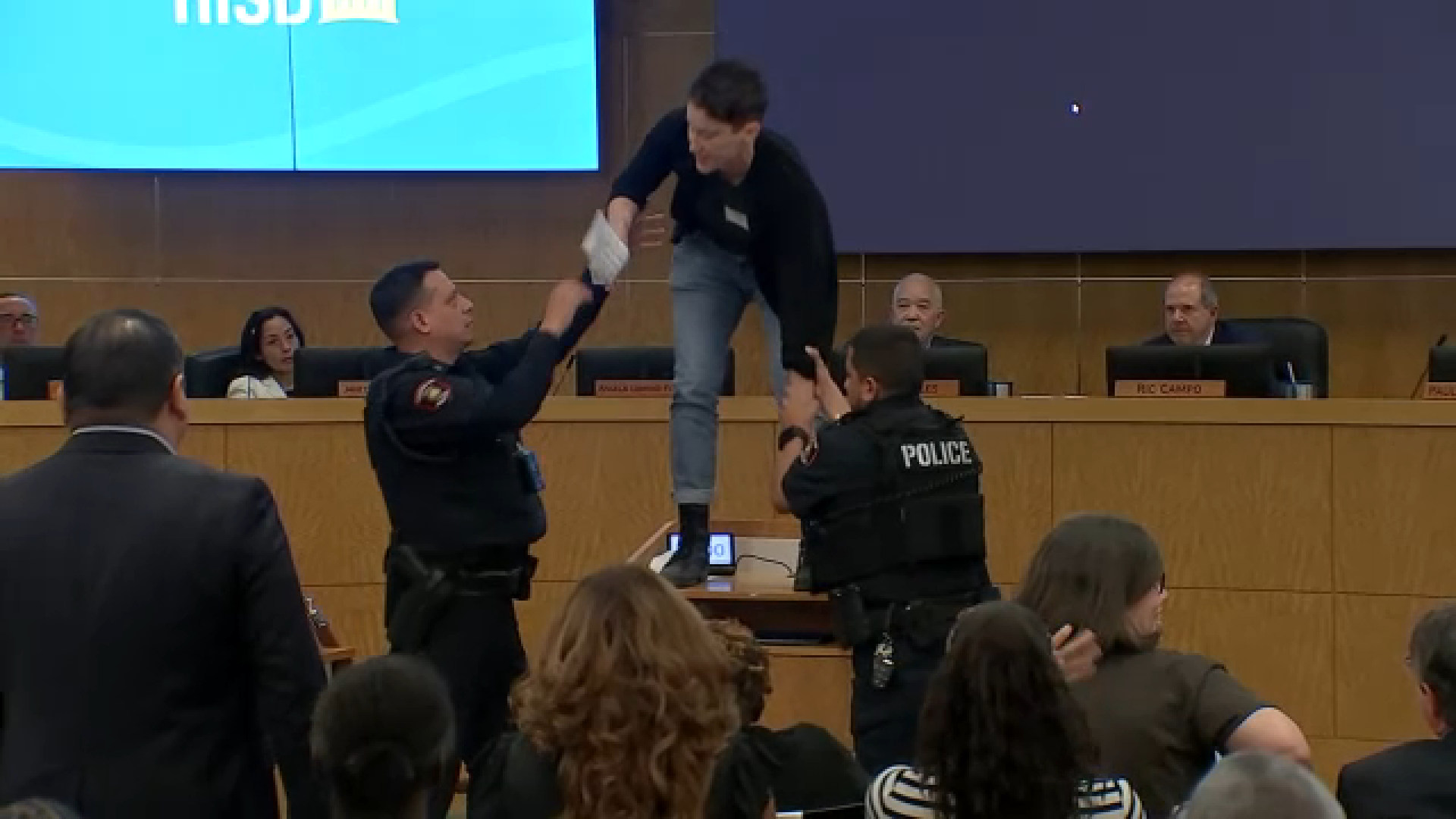A person was escorted from the building after standing on a podium during an HISD meeting on school closures after her time to speak ran out.